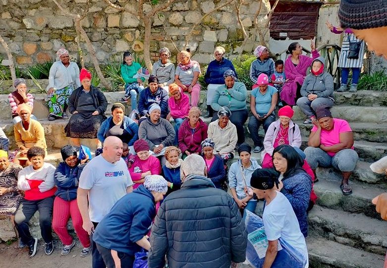 Community members gathered on outdoor steps during a Salt and Light Foundation outreach